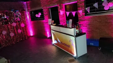 Bar setup with pink lighting and decorations.
