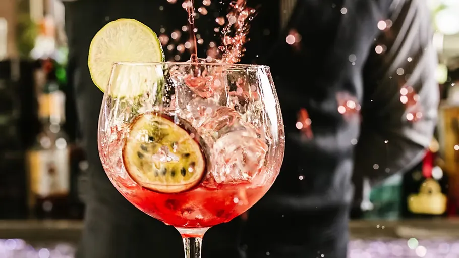 Cocktail splashing with lime and ice garnish.