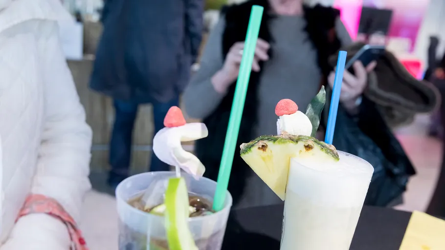 Two drinks with straws on table, blurry background.