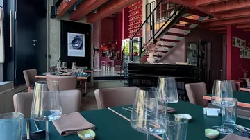 Elegantes Restaurant mit Tischen, Gläsern und Treppe.