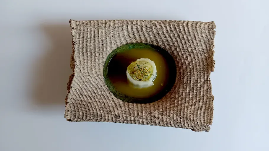 Soup with garnish on rustic fabric surface.