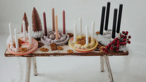 Candles on rustic wooden table, decorated festively.