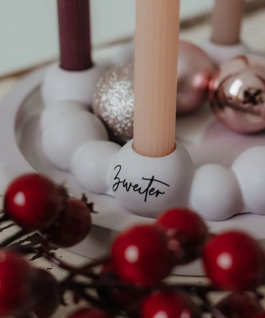 Kerzen und Kugeln auf festlichem Kranz.