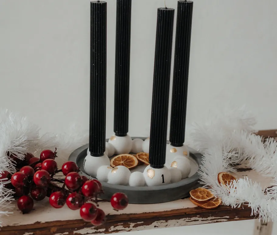 Black candles on decorated wreath with berries.
