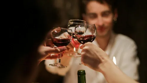 People toasting with red wine glasses.