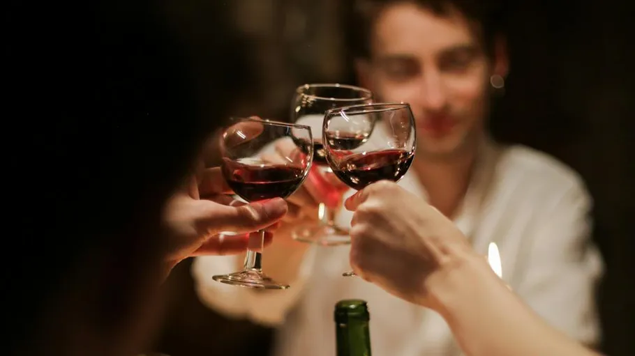 People toasting with red wine glasses.