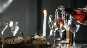 Wein wird in Glas auf elegantem Tisch gegossen.
