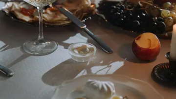 Eleganter Esstisch mit Früchten und Kerze.