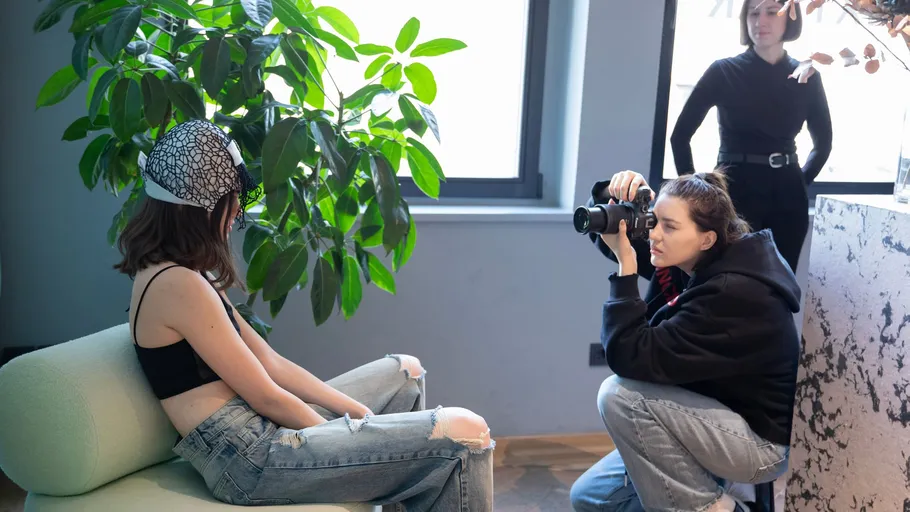 Fotograf macht Innenaufnahme eines sitzenden Models.