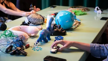 Diverse objects on table with hands interacting.