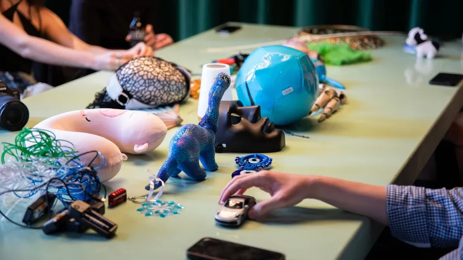 Diverse objects on table with hands interacting.