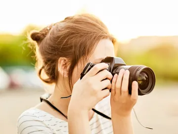 Person fotografiert mit Kamera bei Sonnenuntergang im Freien.