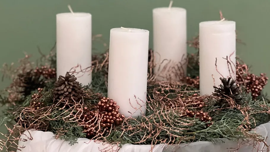 Four white candles in decorative wreath.