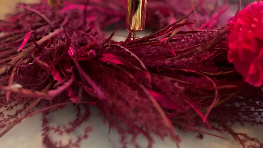 Rotes Blumenarrangement mit goldenem Akzent.