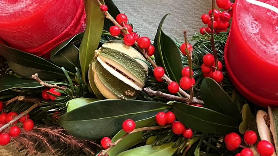 Dekokranz mit roten Kerzen und Beeren.