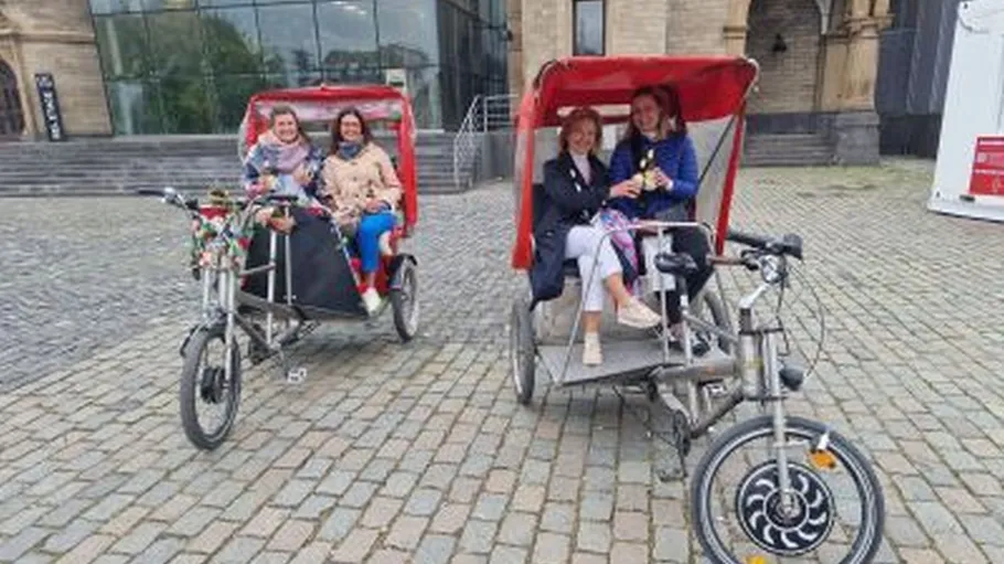Two rickshaws with passengers on cobbled street.
