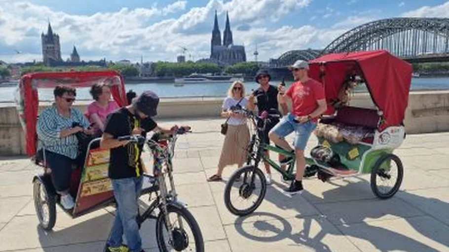 Personen mit Rikscha nahe dem Kölner Dom.