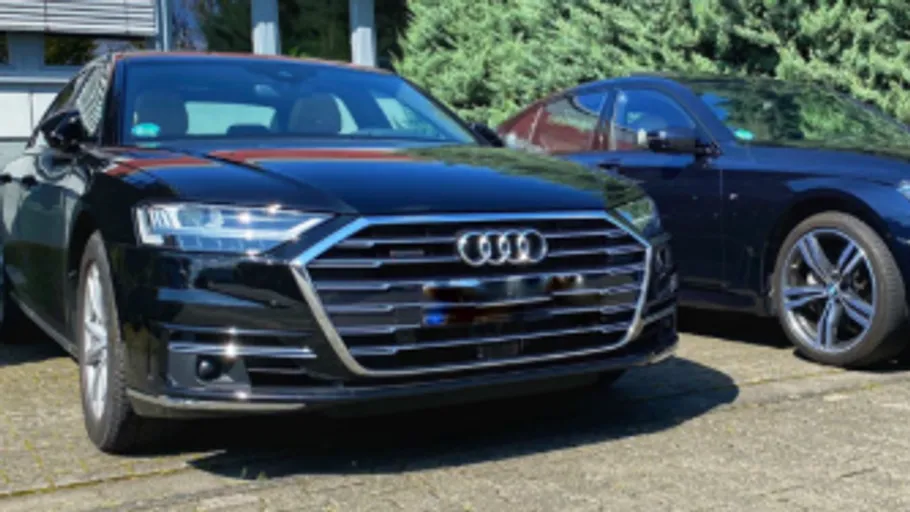 Two parked cars on driveway, sunny day.
