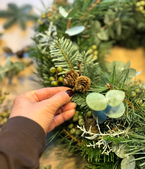Hand adjusting pinecones on a decorative wreath.