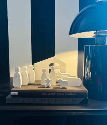 Krippenszene auf Büchern neben Lampe.