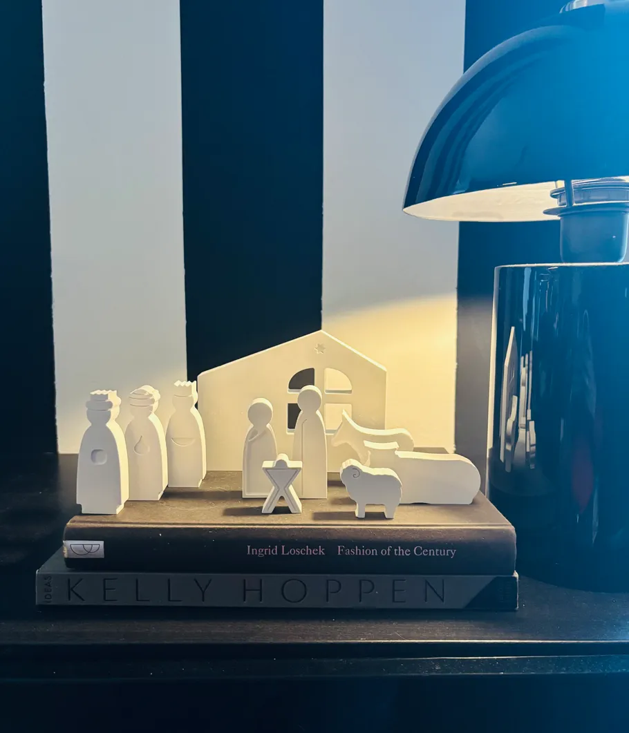 Krippenszene auf Büchern neben Lampe.