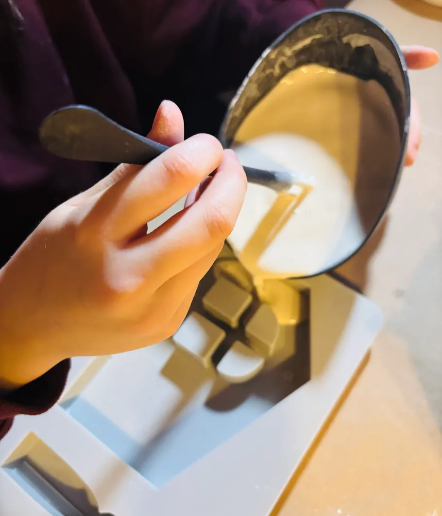 Person pouring mixture into geometric mold.