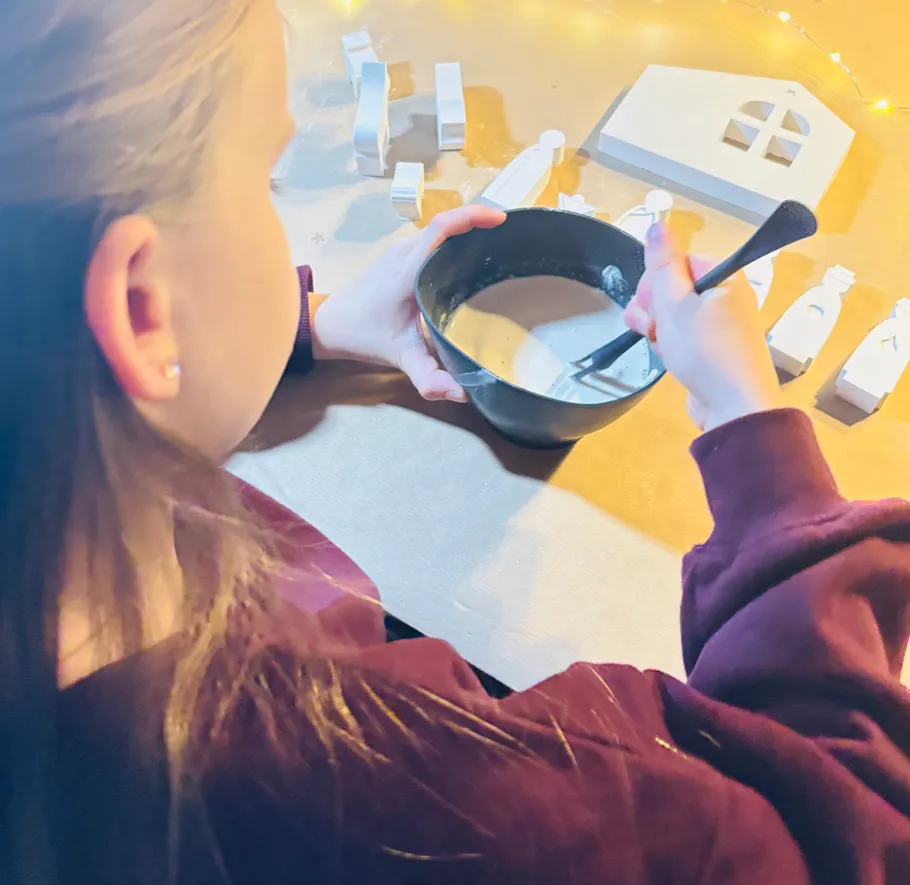 Person stirring mixture with white decorations nearby.