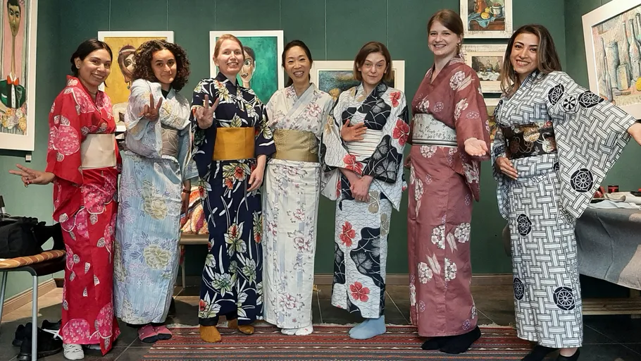 Sieben Frauen in Kimonos posieren in Galerie.