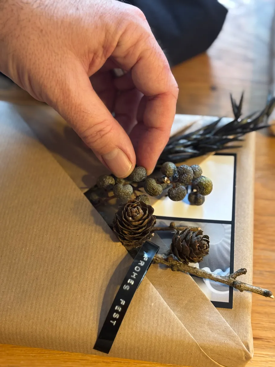 Hand placing decoration on wrapped gift.