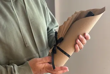 Person holding wrapped gift with ribbon.