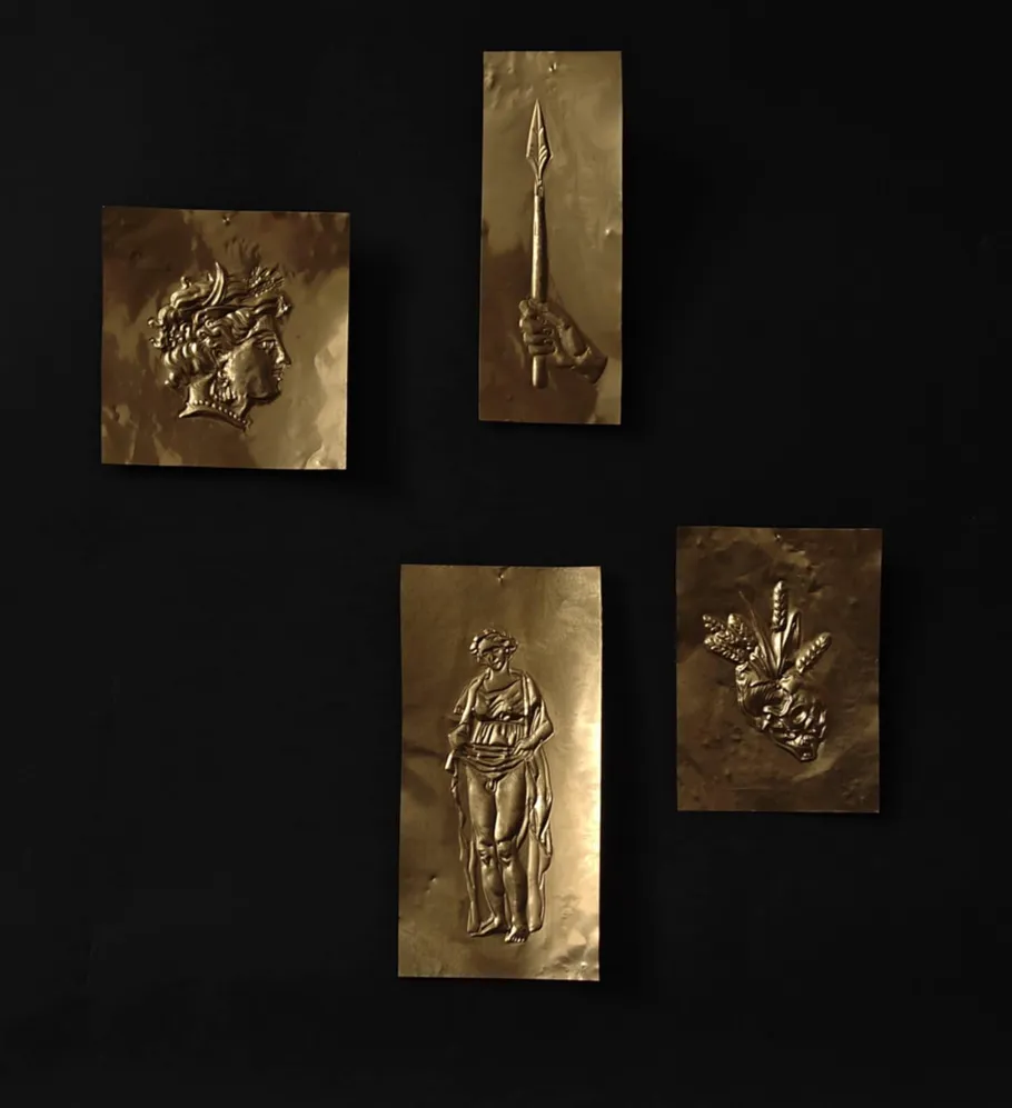 Vier geprägte Goldtafeln auf schwarzem Hintergrund.