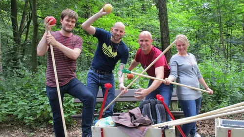 Four people holding garden tools in the forest.