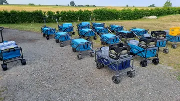 Blue carts and crates on gravel path.