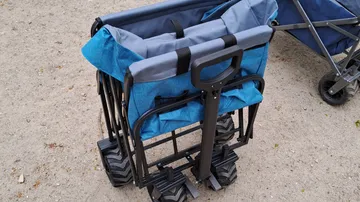 Folded wagon on dirt ground, blue fabric.