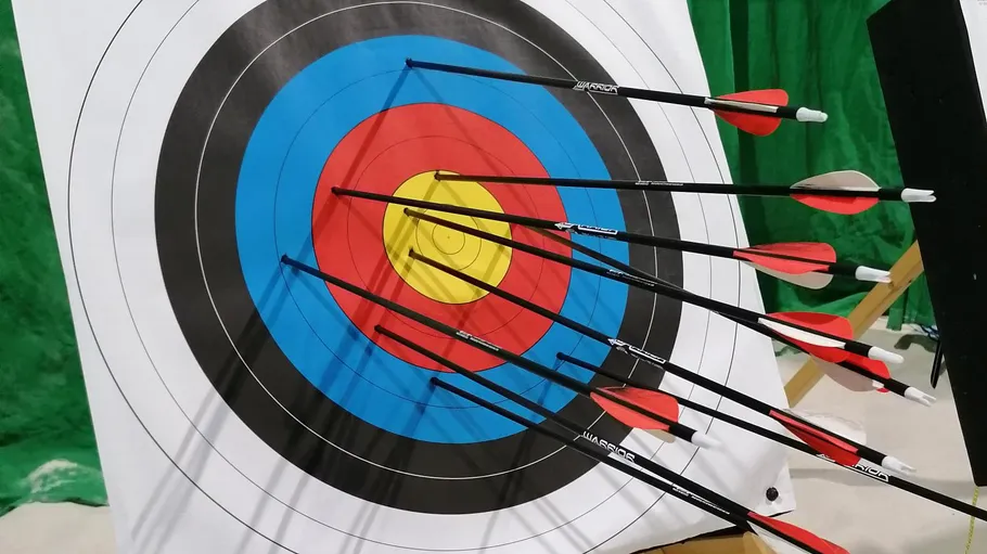 Zielscheibe mit Pfeilen in Scoring-Zonen.