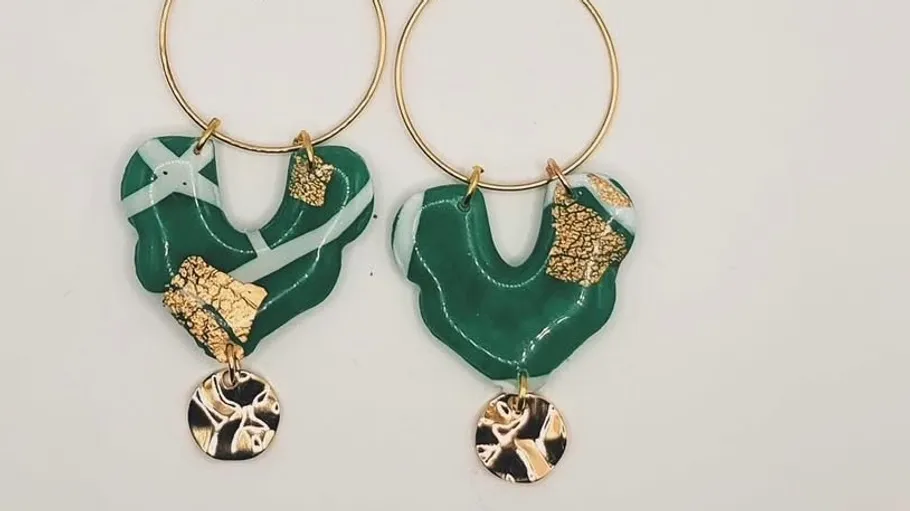 Green earrings with gold accents on plain background.