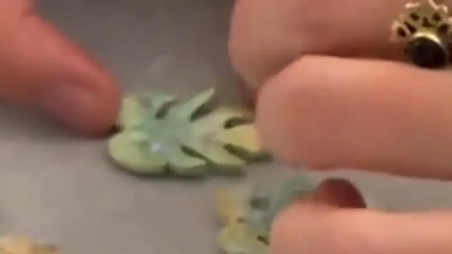 Hands crafting clay leaves on table.