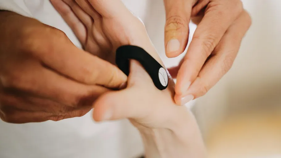 Person attaching black band to another's finger.