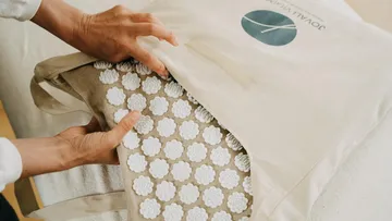 Hände legen Akupunkturmatte in eine Tasche.
