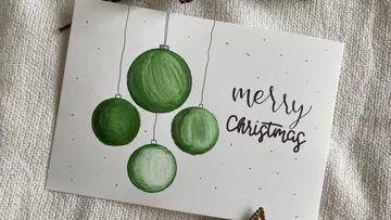 Christmas card with green ornaments, says 'Merry Christmas'.