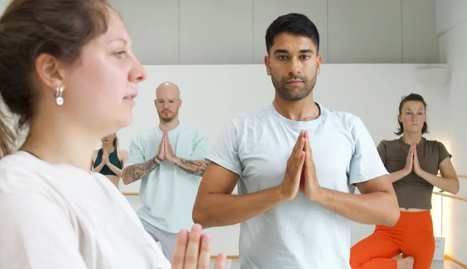 Personen praktizieren Yoga in einem hellen Raum.