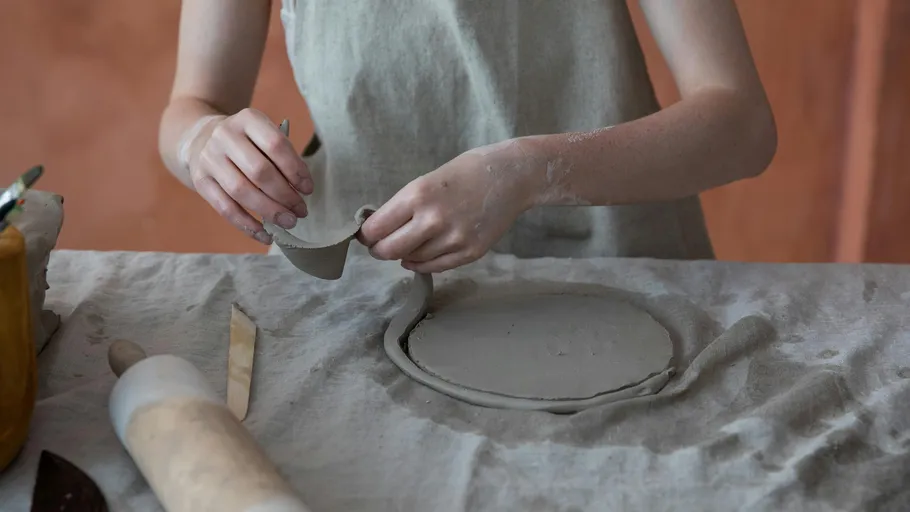 Person shaping clay on a table.