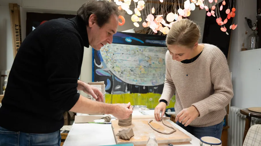 Two people sculpting clay in art studio.