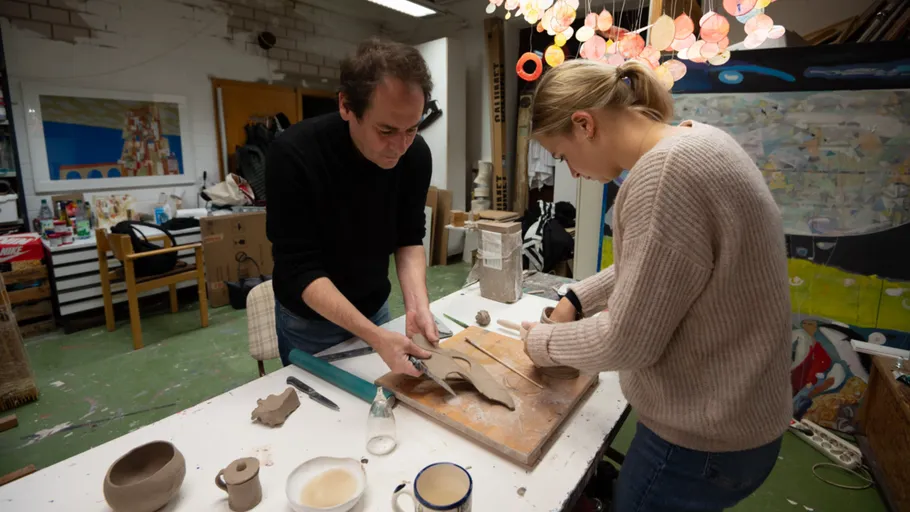 Two people crafting pottery in an art studio.