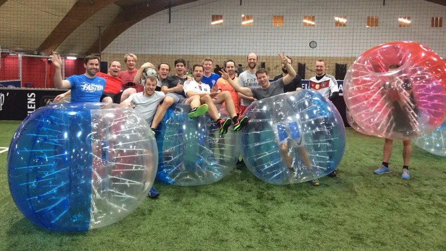 Group posing inside inflatable bubbles on grass.