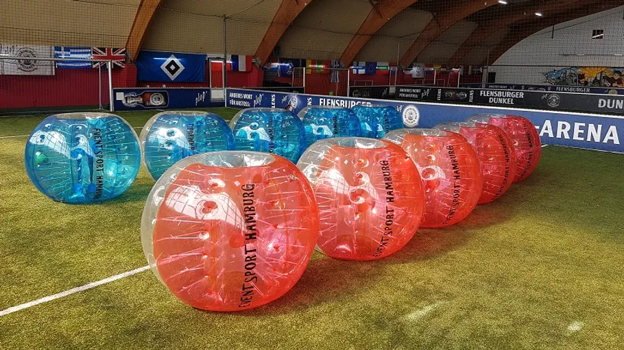 Bunte aufblasbare Bälle auf Hallenfußballfeld.