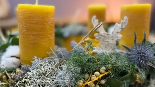 Yellow candles among Christmas ornaments and greenery.