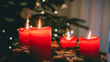 Rote Kerzen leuchten auf Adventskranz drinnen.