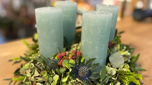Blue candles on a green floral wreath.