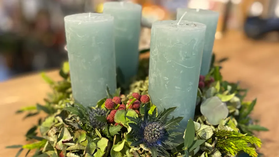 Blue candles on a green floral wreath.